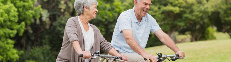 Ein älteres Ehepaar fährt gemeinsam in der Natur Fahrrad.